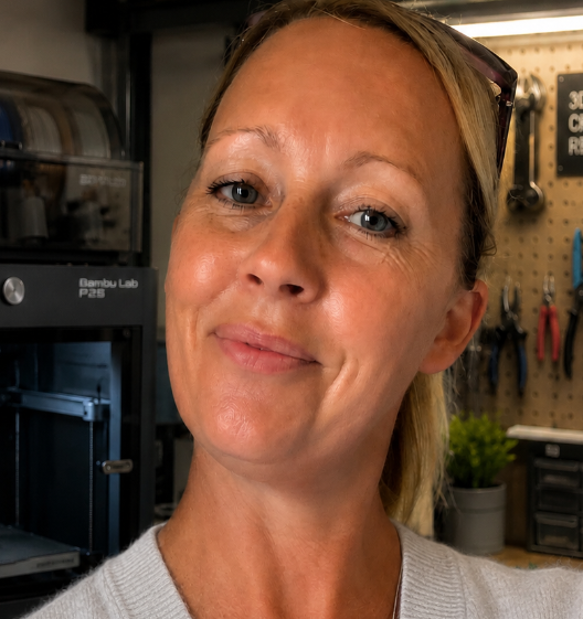 Woman in a workshop with 3D printing equipment in the background