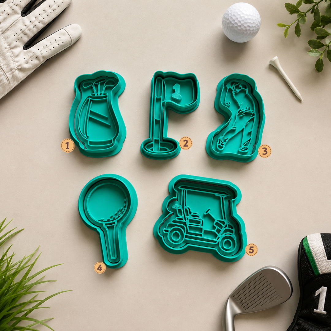 Five teal golf-themed cookie cutters arranged on a beige surface with golf props around them: a glove, golf ball, tees, plant leaves, and a golf club. The cutters are shaped like a golf bag, flag, hole flag, golf club head, and golf cart.