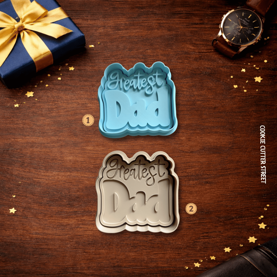 Two cookie cutters with 'Greatest Dad' text on a wooden surface with a gift and watch.