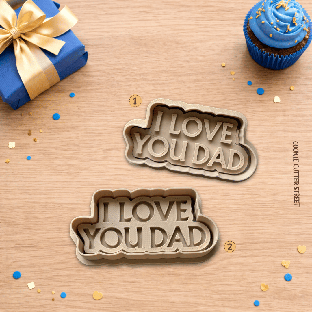 Cookie cutters with 'I Love You Dad' text on a wooden surface with a gift and cupcake.
