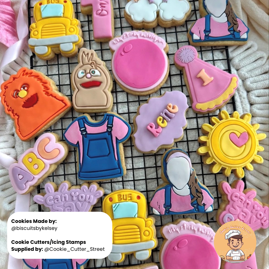 Colorful cookies with various designs on a cooling rack, featuring cookie cutters and stamps.