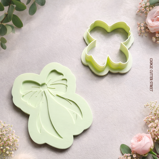 Multi-level bow cookie cutter and embosser creating elegant ribbon-shaped cookies with detailed layered design.