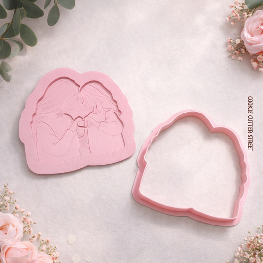 Mummy and Daughter Pink cookie cutter with heart-shaped design on a light surface with flowers around.