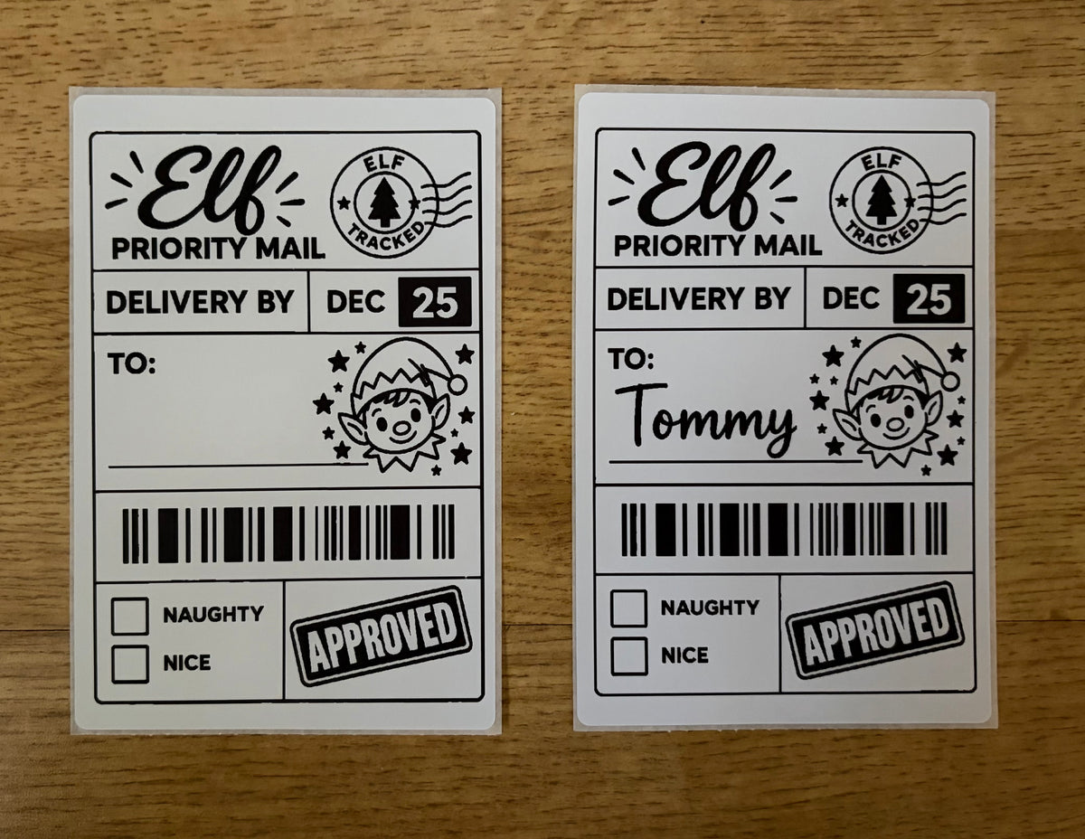 Two white Elf Priority Mail tracking stickers with black printed text and graphics, displayed side-by-side on a light brown wooden surface.