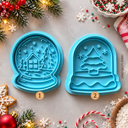 Two Christmas snow globe icing stamps featuring a snowy cottage winter wonderland and Christmas tree design, 3D printed by Cookie Cutter Street.