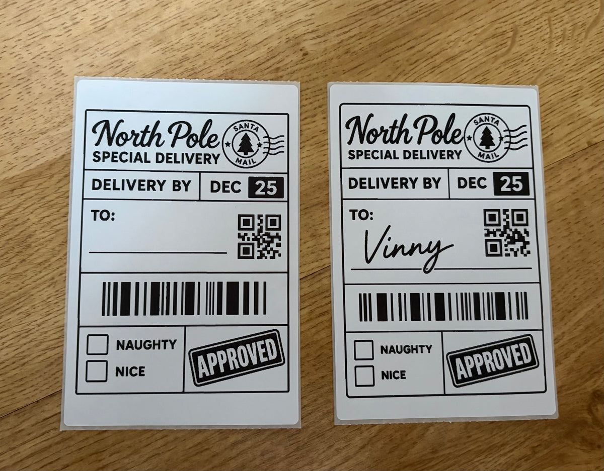 Two North Pole Special Delivery novelty labels on a wooden surface. One has a barcode and 'APPROVED' stamp, and the other has a handwritten 'To: Vinny' signature.