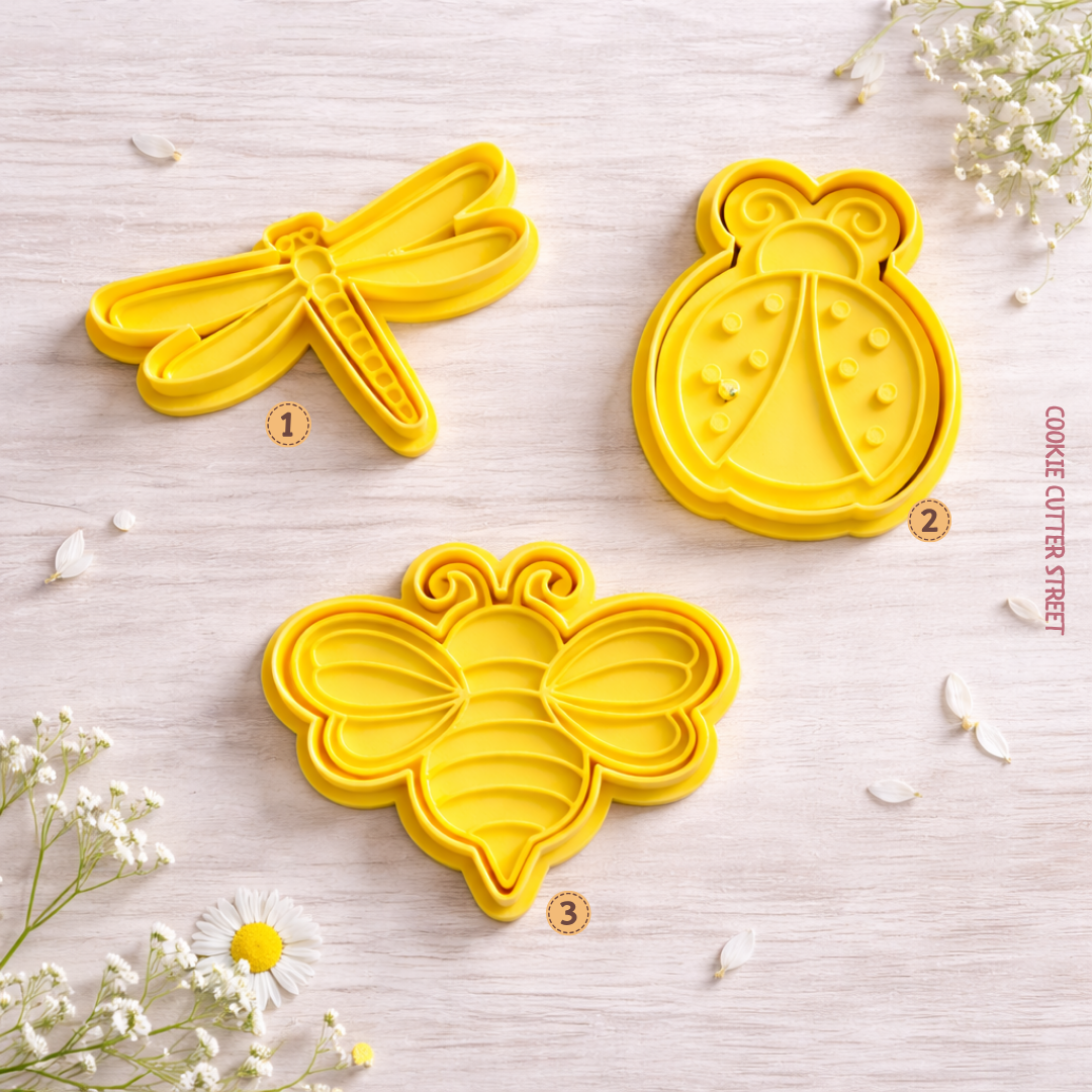 Yellow insect cookie cutters with matching imprint icing stamps featuring a dragonfly, ladybird, and bee on a soft spring background.
