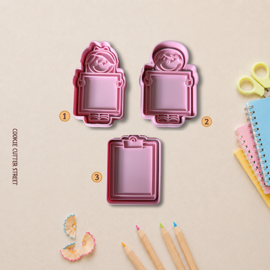 School-themed cookie cutter set featuring boy and girl characters holding blank plaques plus a clipboard design for personalised cookies.