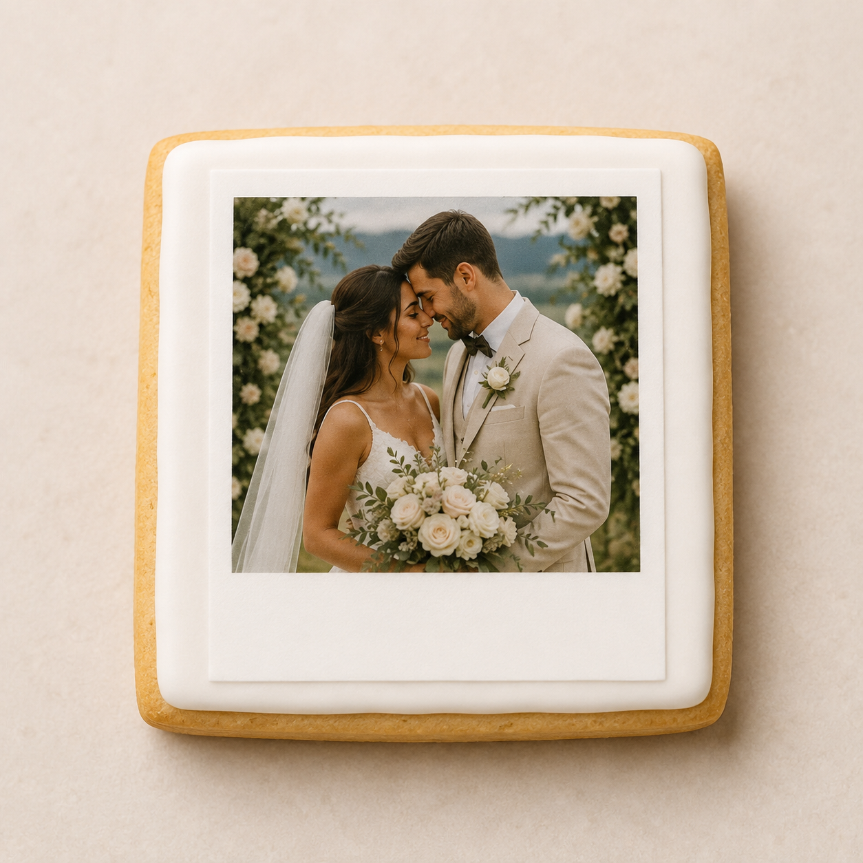 A square iced-out sugar cookie with a custom printed wedding photo in the center, set against a neutral beige background.
