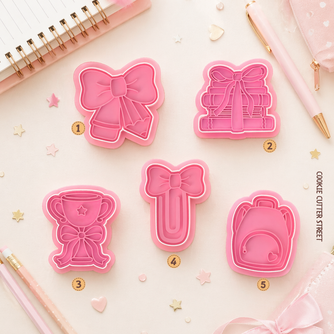 School-themed cookie stamp and cutter set featuring cute bow-inspired designs including school pencil, books, a trophy, a paperclip and a backpack.